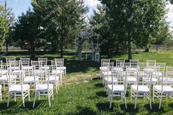 Ceremonia de boda al aire libre con arco de flores y sillas decoradas